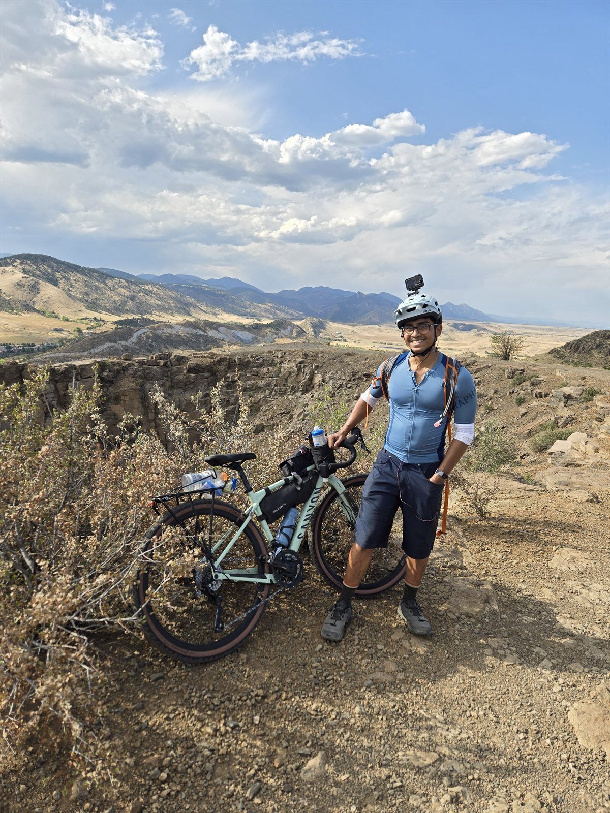 Ahmed with his gravel bike on a ridge, mountains behind